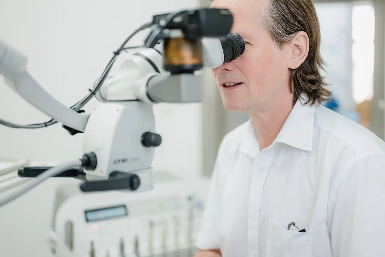 Zahnarzt schaut bei der Behandlung durch ein optisches Gerät